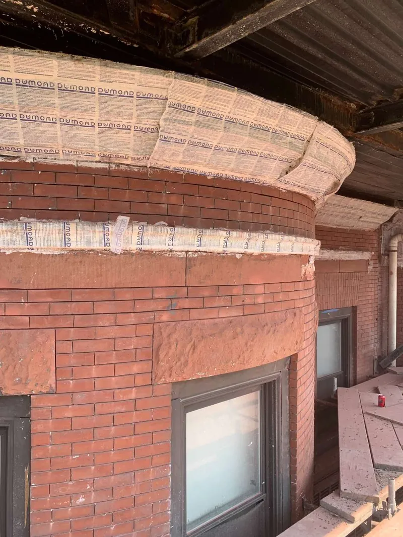 Curved brick bay and corbelled band after paint removal
