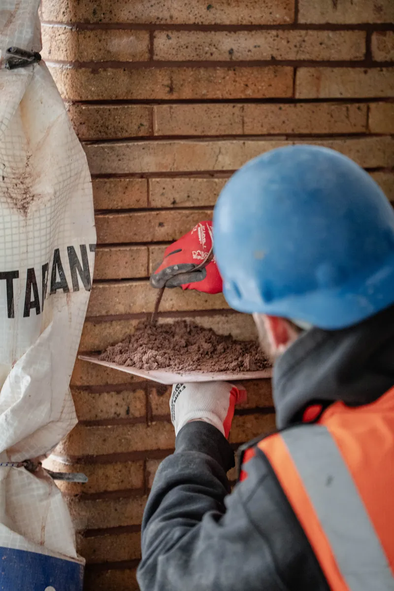 Mason repointing a brick pier by hand